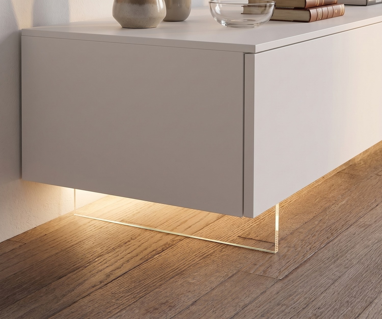 Socle TV transparent de Livitalia pour meuble bas suspendu avec éclairage LED sur parquet dans le salon.