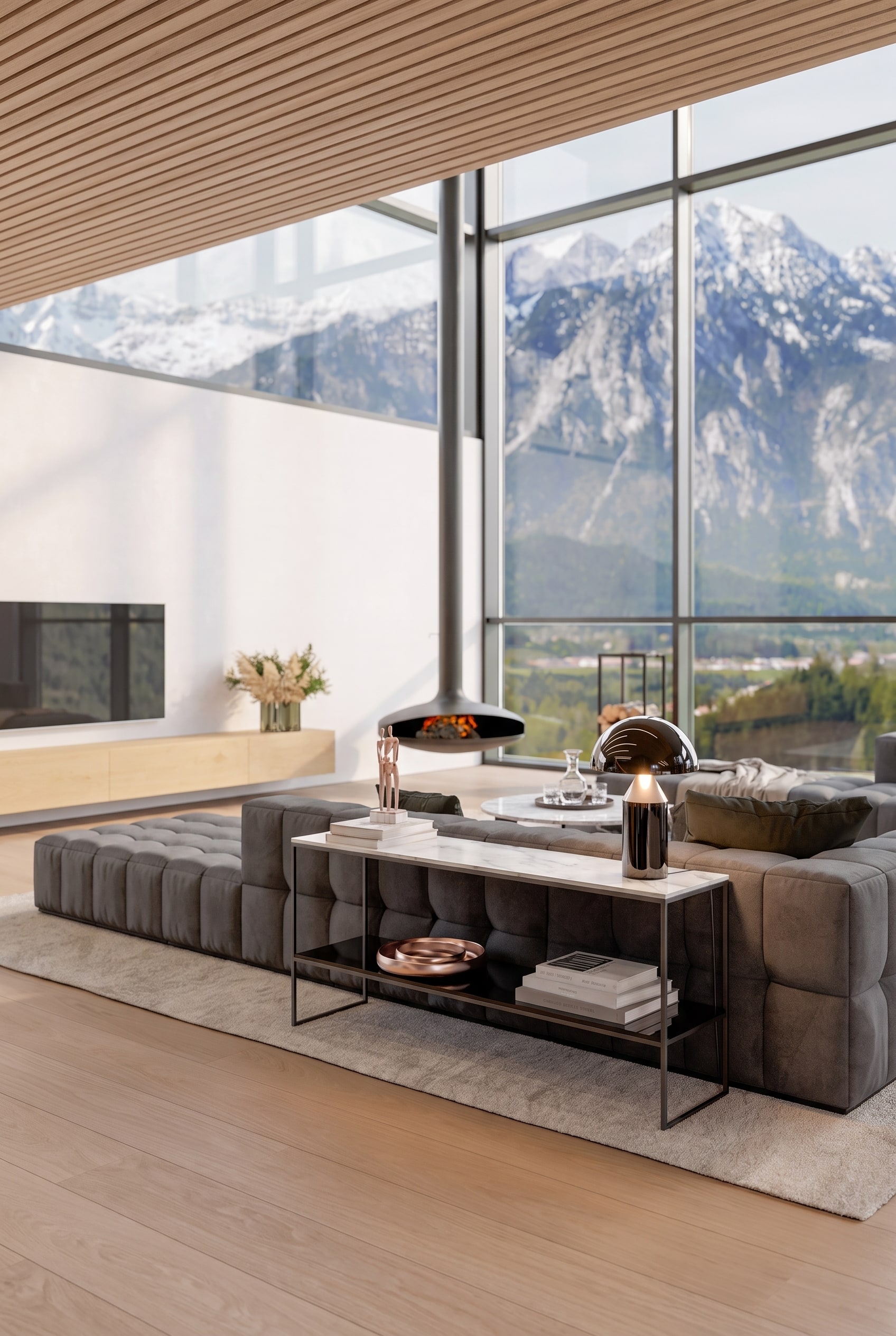 Vue arri&egrave;re d'un canap&eacute; gris dans le salon, avec derri&egrave;re une console m&eacute;tallique &eacute;troite et minimaliste avec plateau en marbre, agr&eacute;ment&eacute;e d'une lampe de table et de livres.