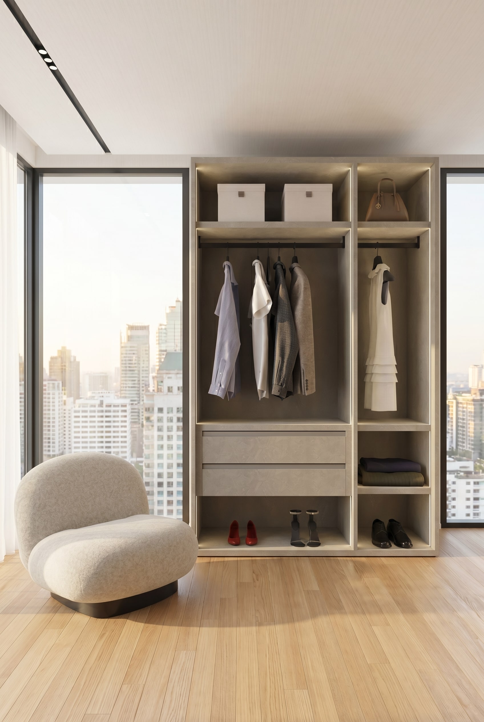 Dressing moderne avec un système d'armoire ouverte sans cadre en greige structuré, des chemises en lin suspendues et un fauteuil lounge dans la lumière chaude du matin