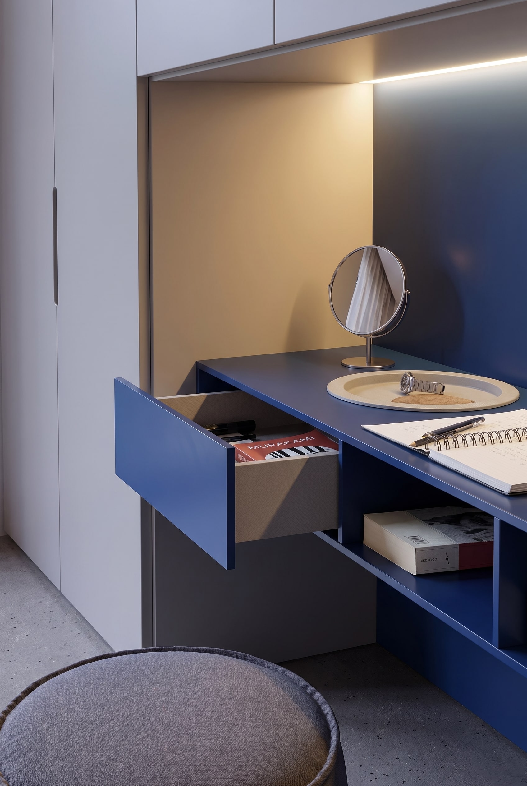 Tiroir bleu ouvert de la coiffeuse avec des livres, à côté d'une étagère ouverte sous le plateau de la table.
