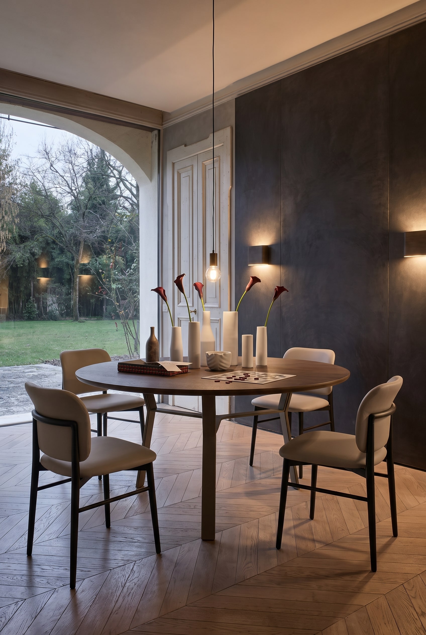 &Eacute;l&eacute;gante salle &agrave; manger avec mur sombre, longue table &agrave; manger avec pi&egrave;tement m&eacute;tallique et &eacute;l&eacute;gantes chaises en cuir couleur taupe