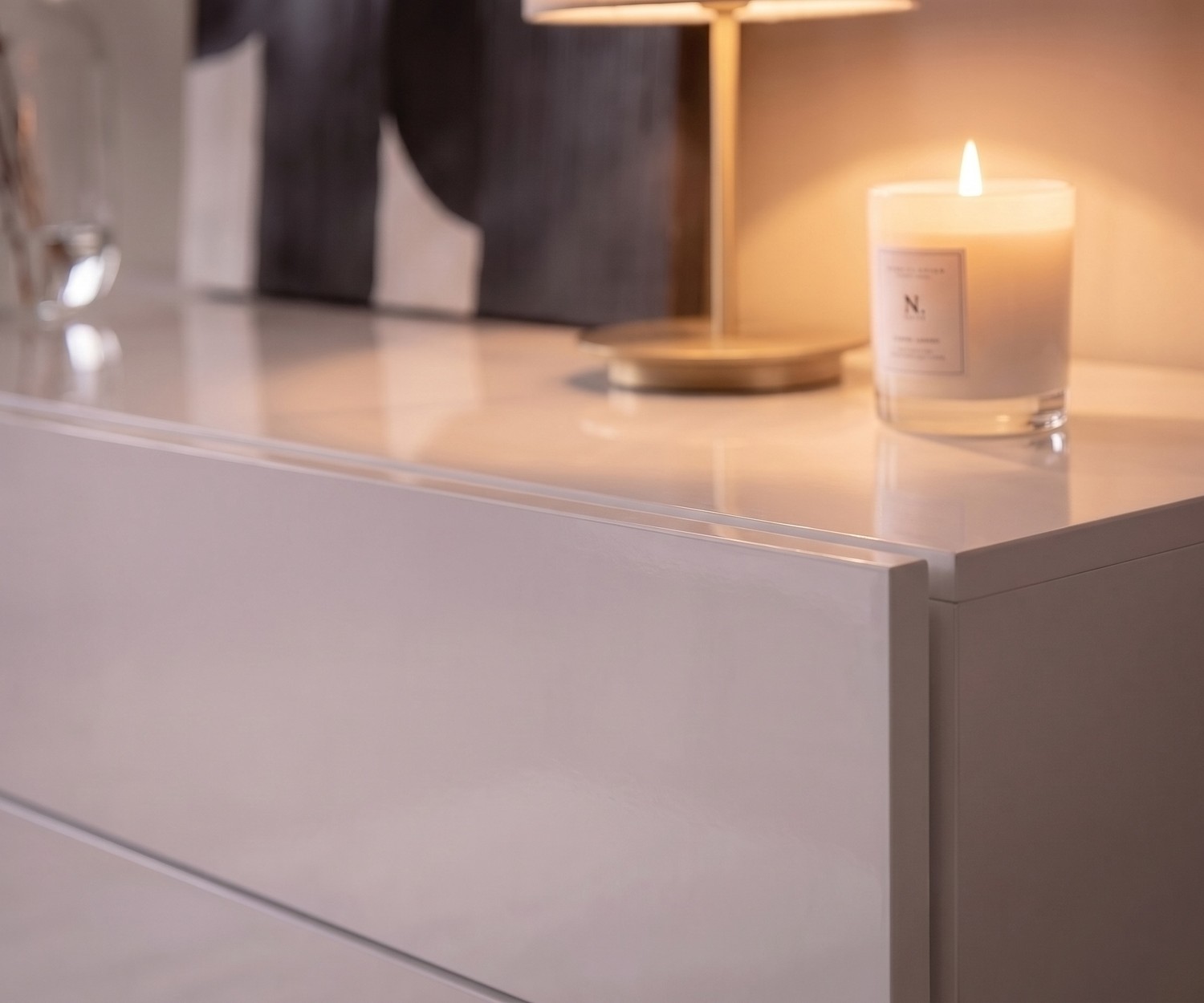 Zwevende commode Novamobili Easy voor de slaapkamer. Moderne witte hoogglans ladekast zonder grepen met sfeervolle kaars.