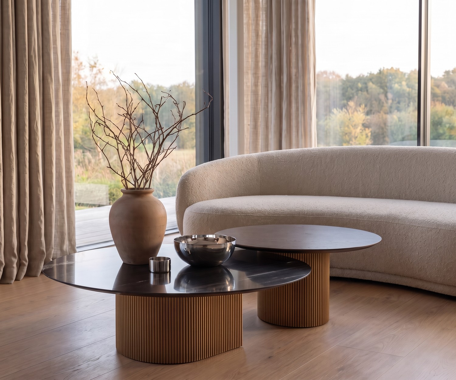 Table basse al2 dakry 006 dans un salon moderne avec canapé bouclé, piétement en bois cannelé et plateau rond.