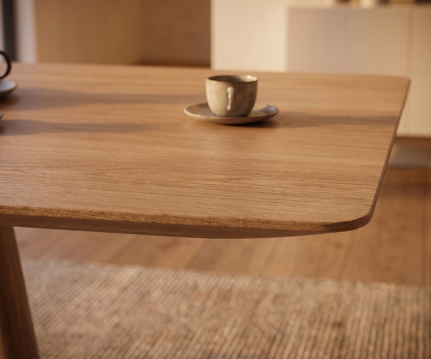 Table de repas mos-i-ko 001 a en chêne clair, zoom sur le coin arrondi du plateau en bois dans une salle à manger moderne.