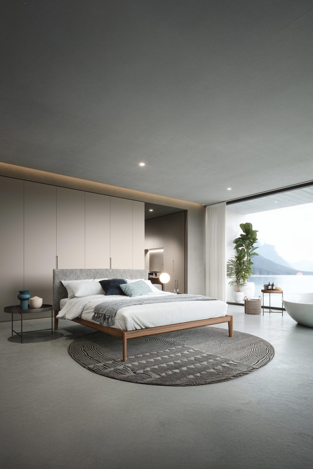 bed-en-kledingkast-met-strakke-designtaal-in-een-ruime-slaapkamer-met-grote-raampartij