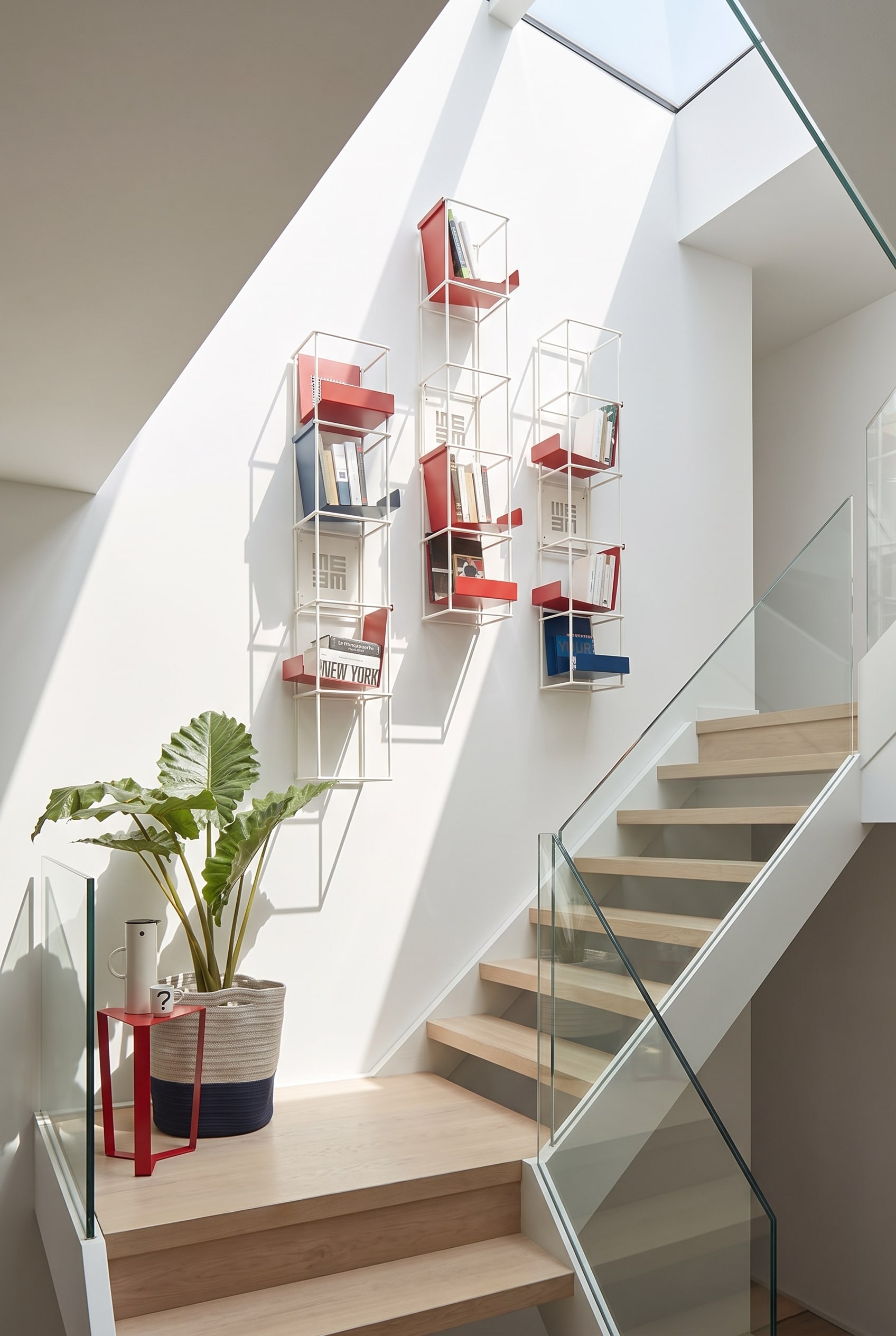Étagère murale modulaire ouverte Livitalia Tetris sur le mur blanc d'une cage d'escalier moderne, remplie de livres et de décoration