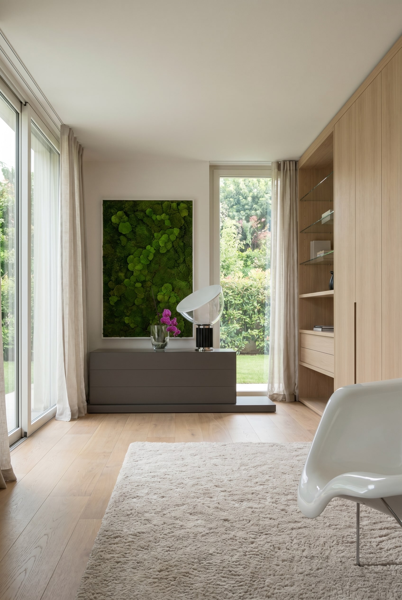 Chambre élégante avec commode basse gris foncé, au-dessus un tableau de mousse et une chaise coque blanche