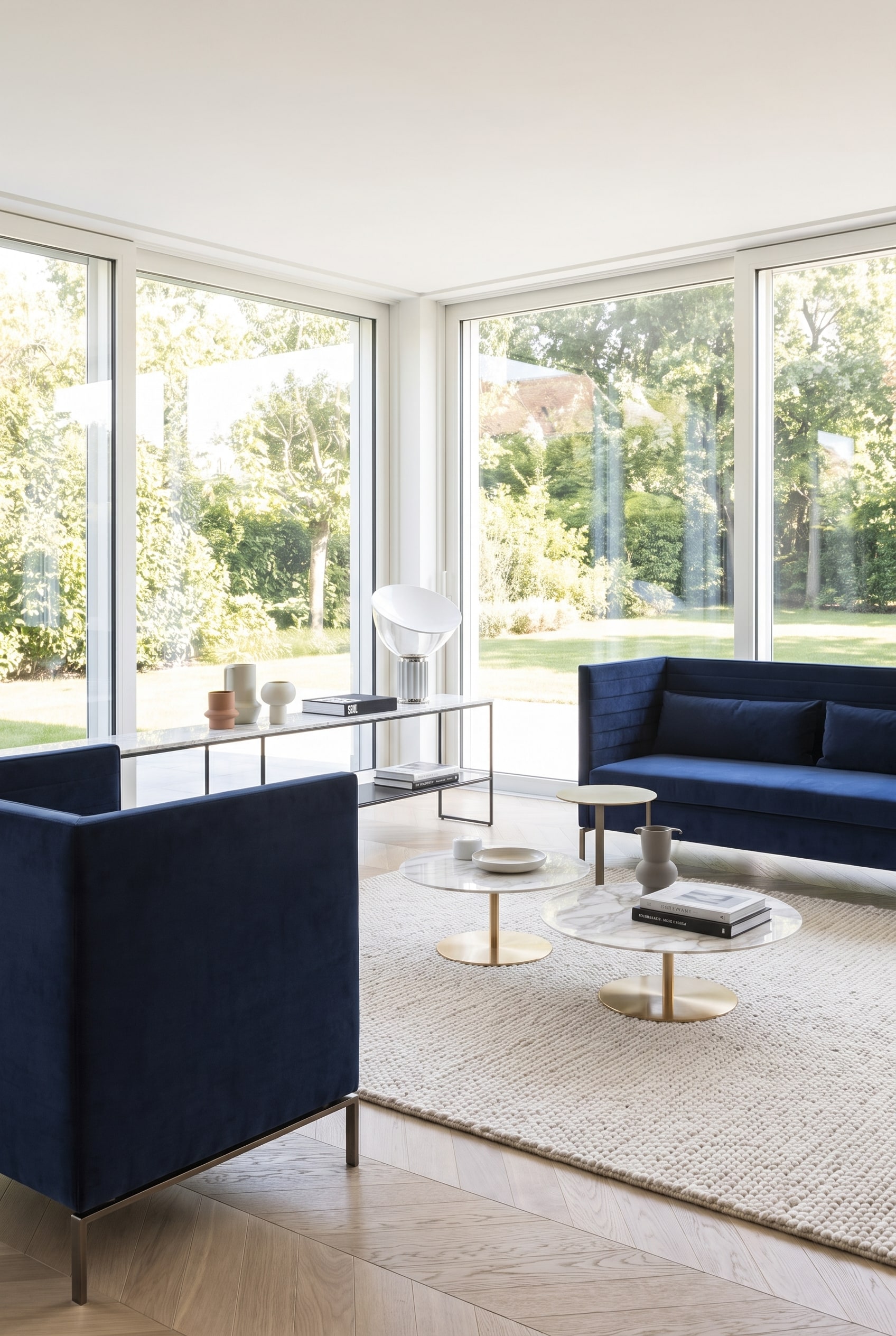 Salon à l'allure spacieuse avec un canapé filigrane bleu foncé sur des patins métalliques élancés, laissant le parquet clair visible.