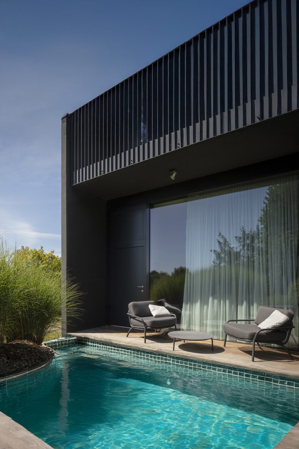 fauteuils-rembourrés-larges-modernes-avec-table-derrière-une-piscine