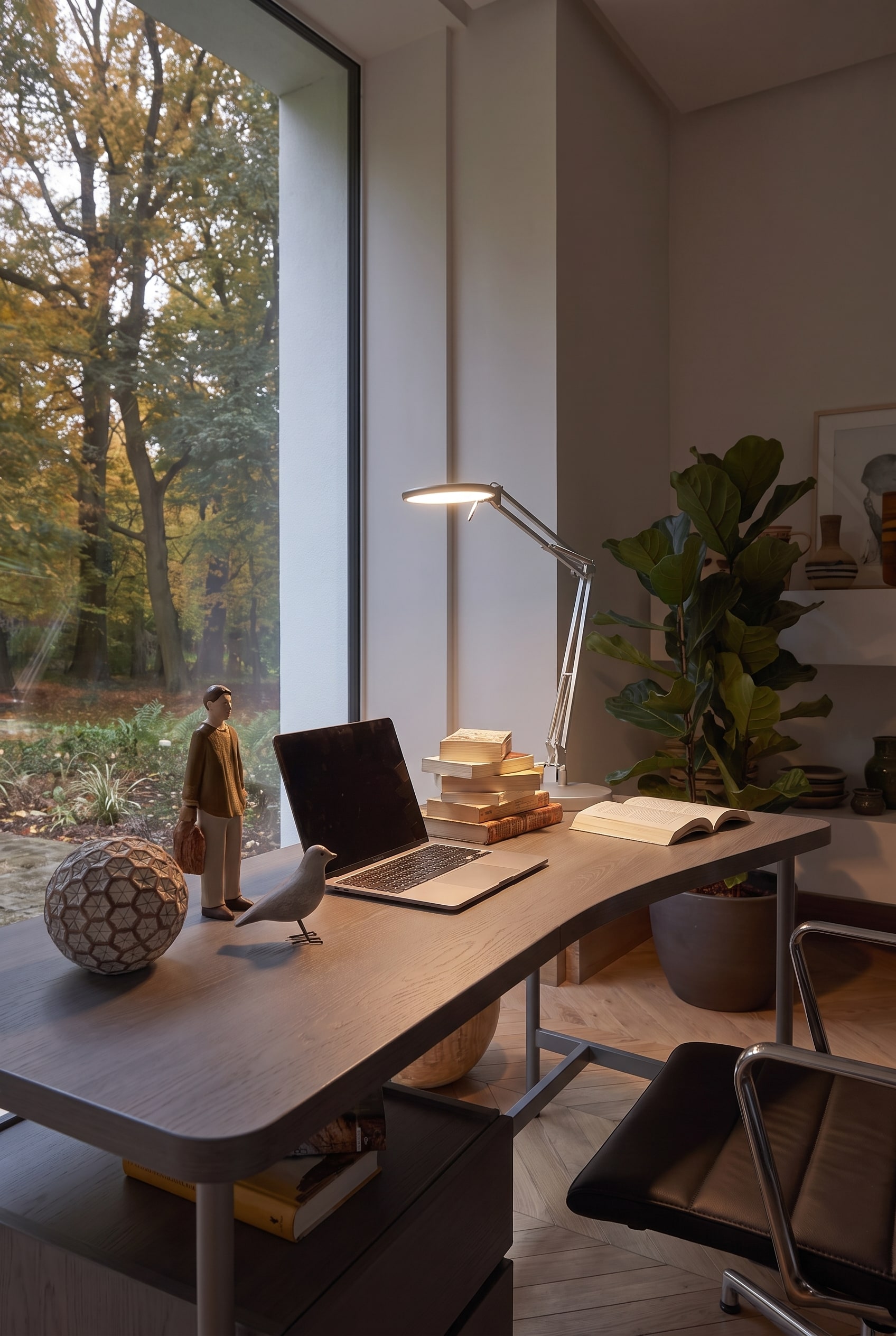 Espace de travail &eacute;clair&eacute; sur le bureau avec une lampe chrom&eacute;e brillante, des figurines en bois et un ordinateur portable.