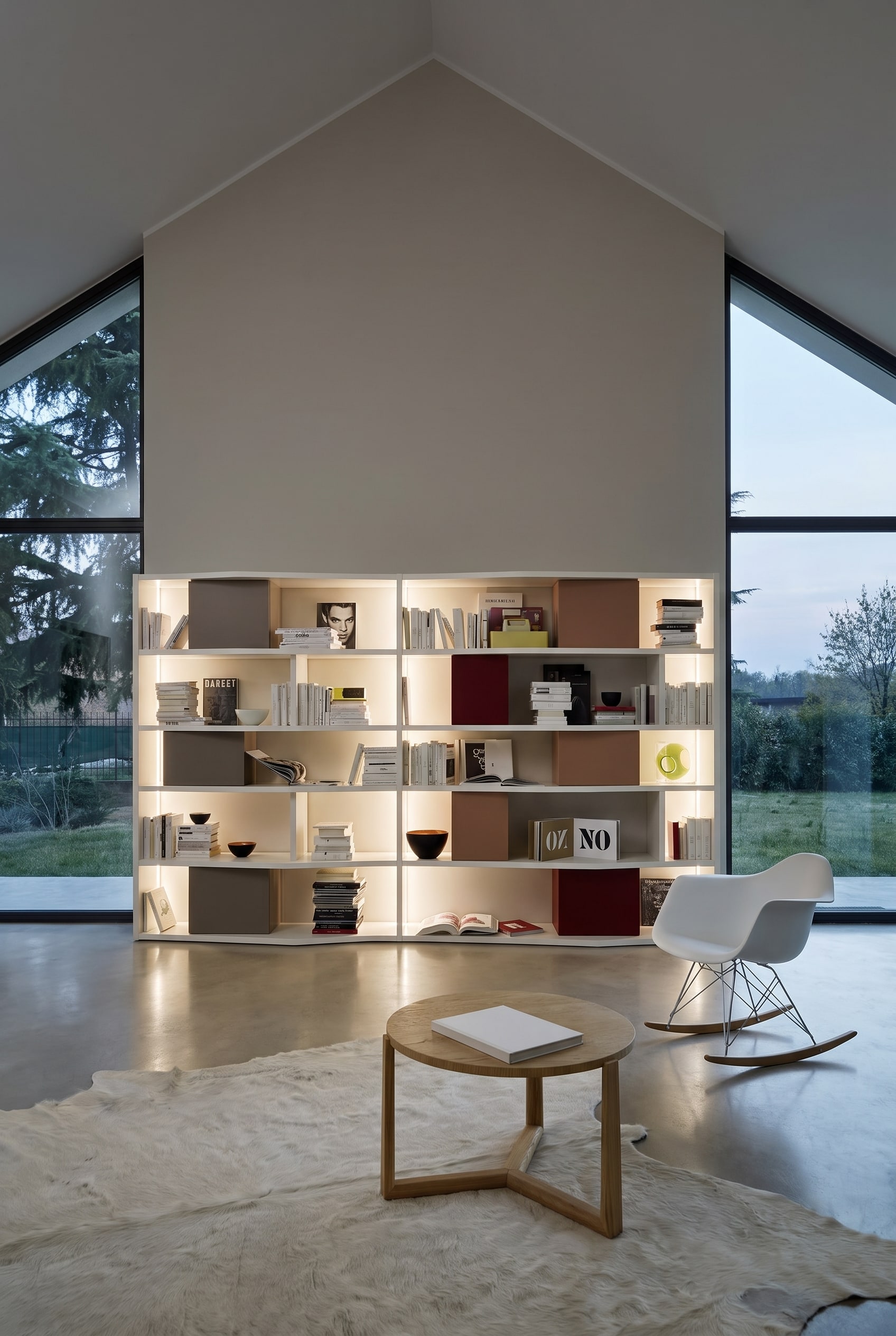 Haute biblioth&egrave;que blanche sur un mur pignon droit dans les combles, garnie de livres et de bo&icirc;tes de rangement color&eacute;es
