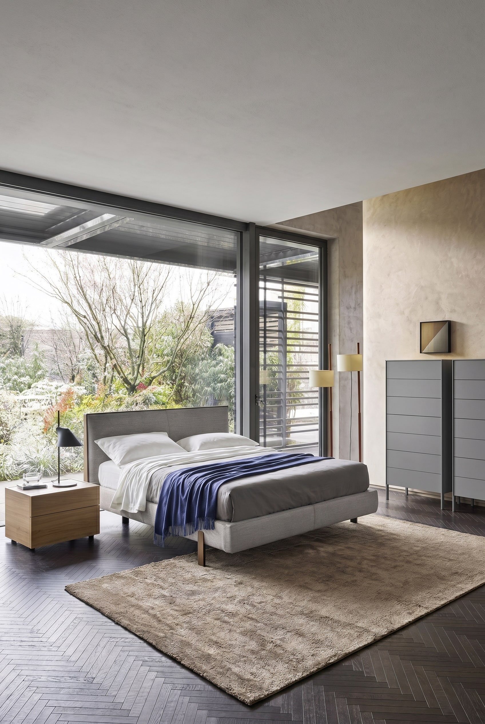 Chambre élégante avec fenêtres pleine hauteur et une commode haute grise moderne sur de fins pieds métalliques
