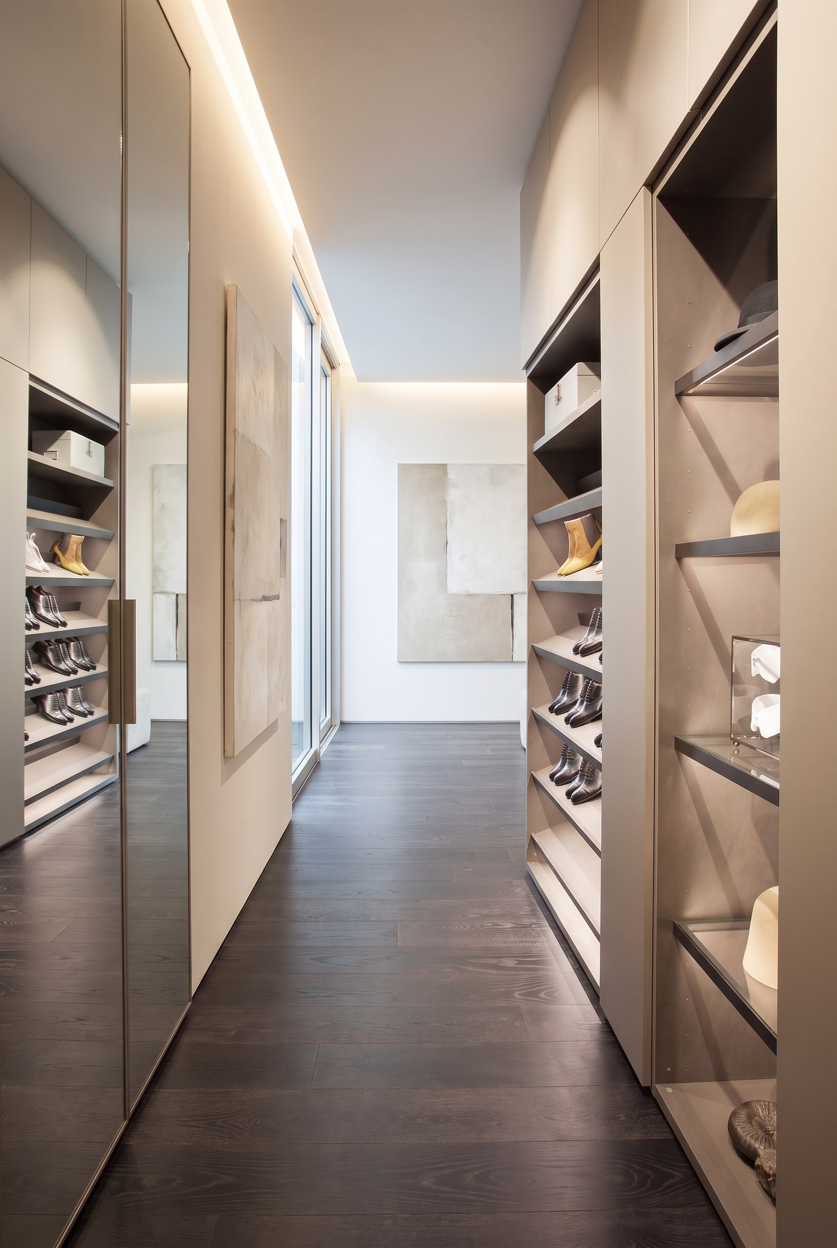 Un meuble à chaussures moderne légèrement ouvert dans l'entrée, qui révèle à l'intérieur des étagères inclinées avec éclairage LED intégré.