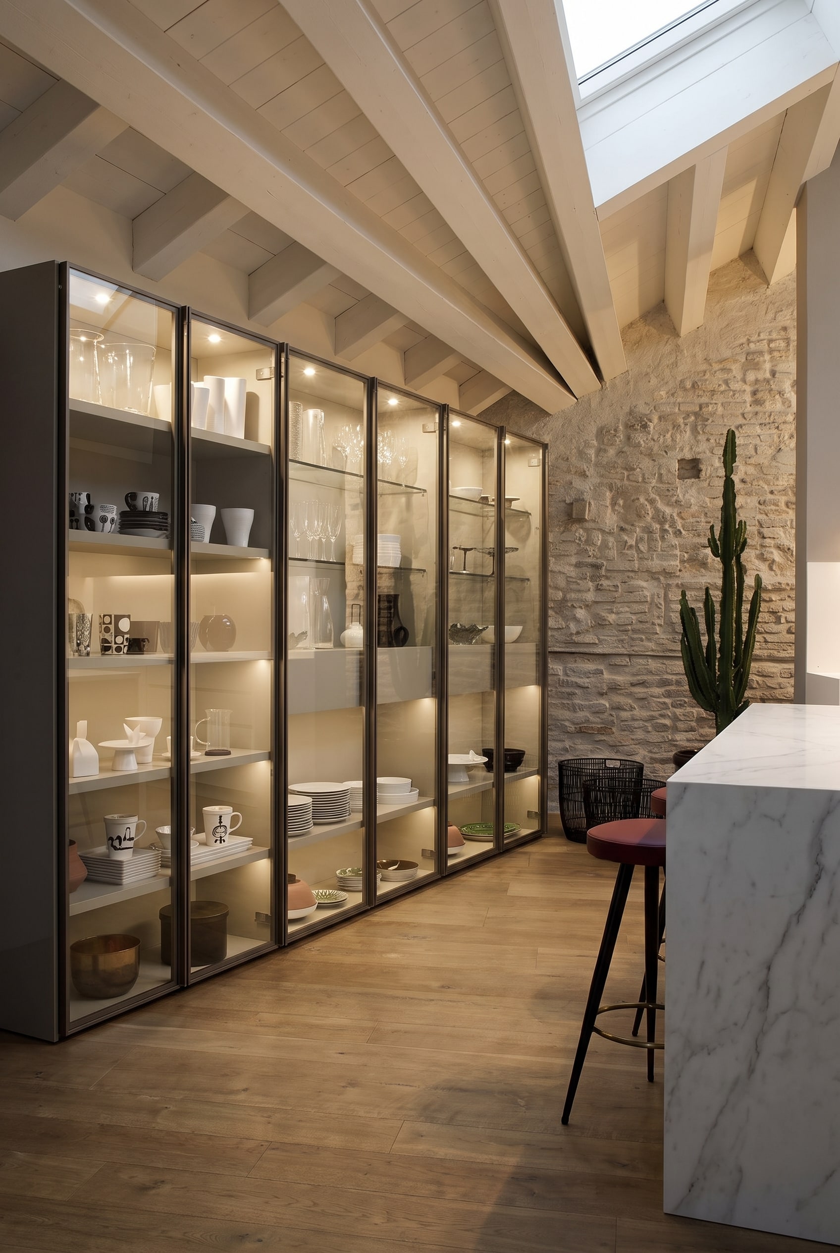 Grande vitrine en verre avec cadre m&eacute;tallique fin et &eacute;clairage int&eacute;rieur LED doux dans une salle &agrave; manger &eacute;l&eacute;gante