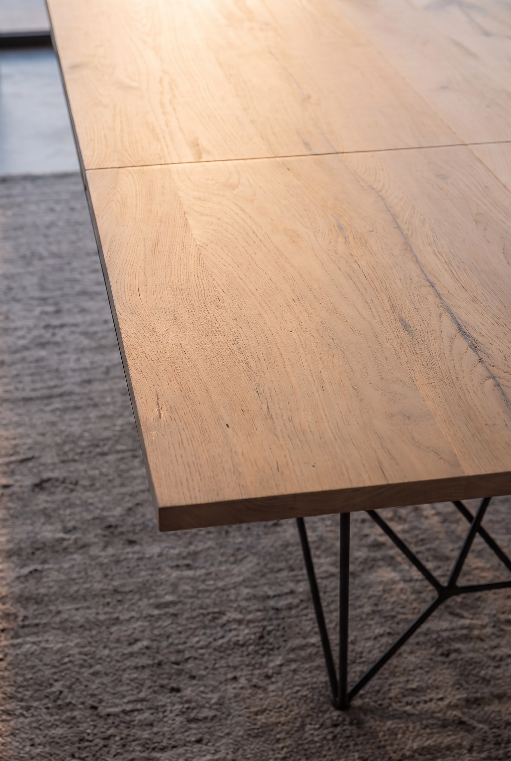 Vue d&eacute;taill&eacute;e du bord en bois et du pi&egrave;tement en m&eacute;tal noir de la table &agrave; manger Ozzio Fil8.