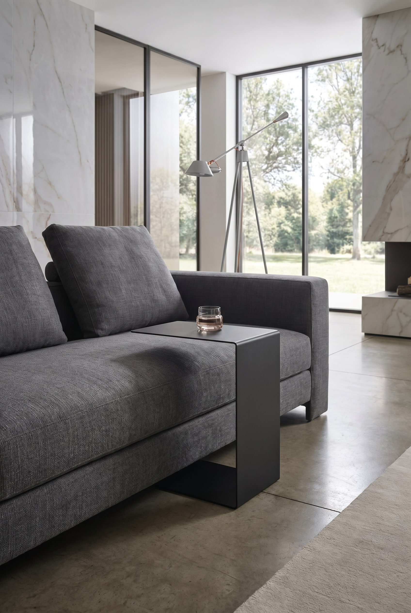 Gros plan d'un canapé en tissu gris avec une table d'appoint en métal noire, minimaliste et en forme de C