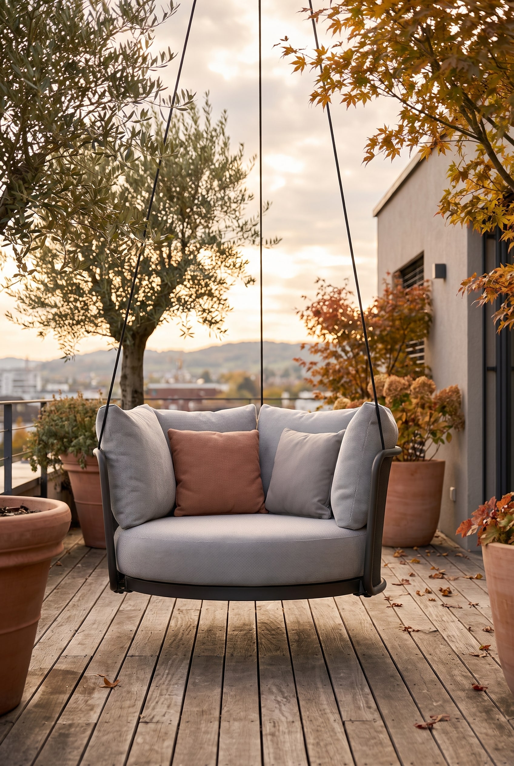 Fauteuil suspendu moderne avec coque d'assise ronde et coussins &eacute;pais, flottant au-dessus d'une terrasse en bois