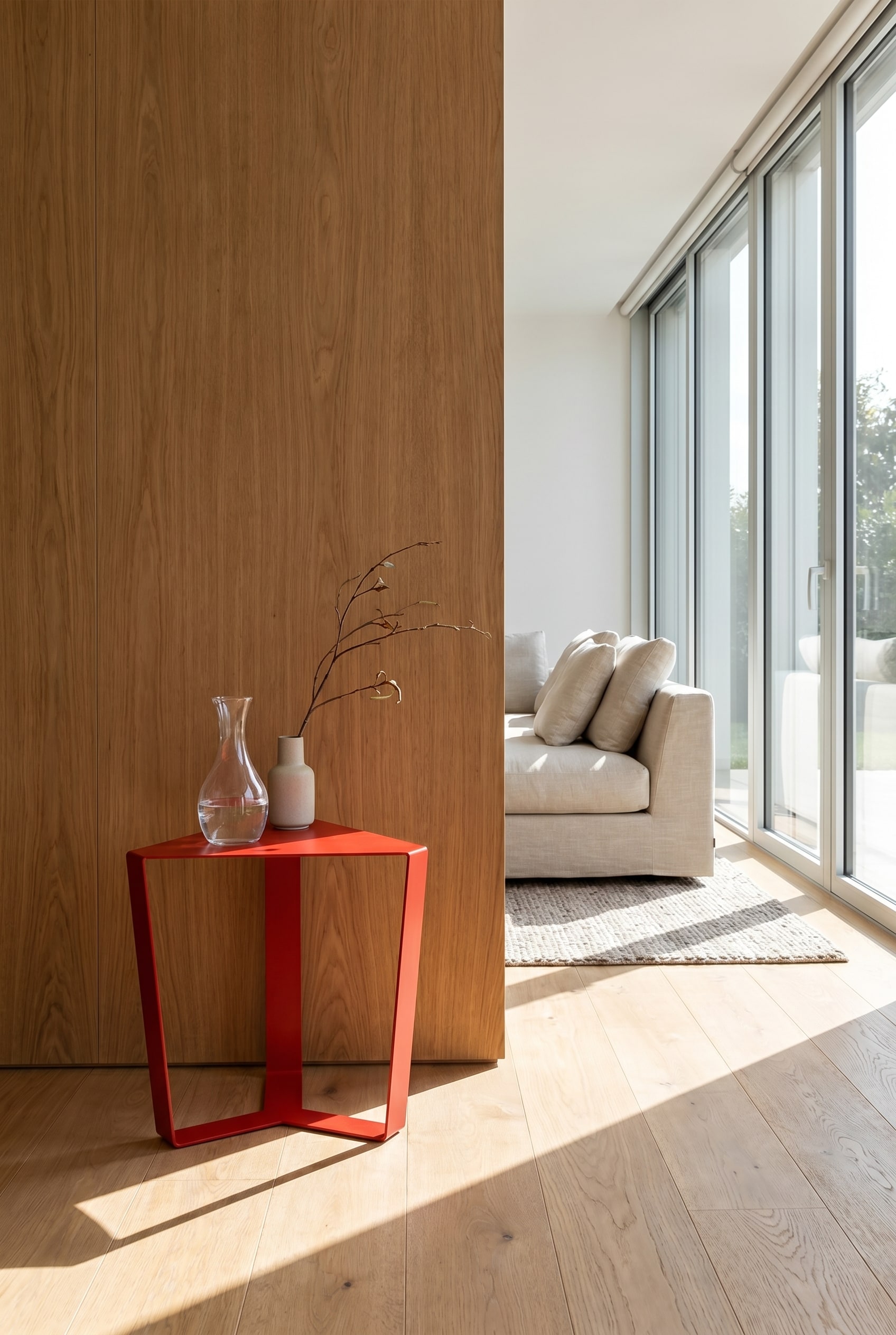 Table d'appoint géométrique minimaliste en métal rouge fin devant un mur massif avec des panneaux de bois