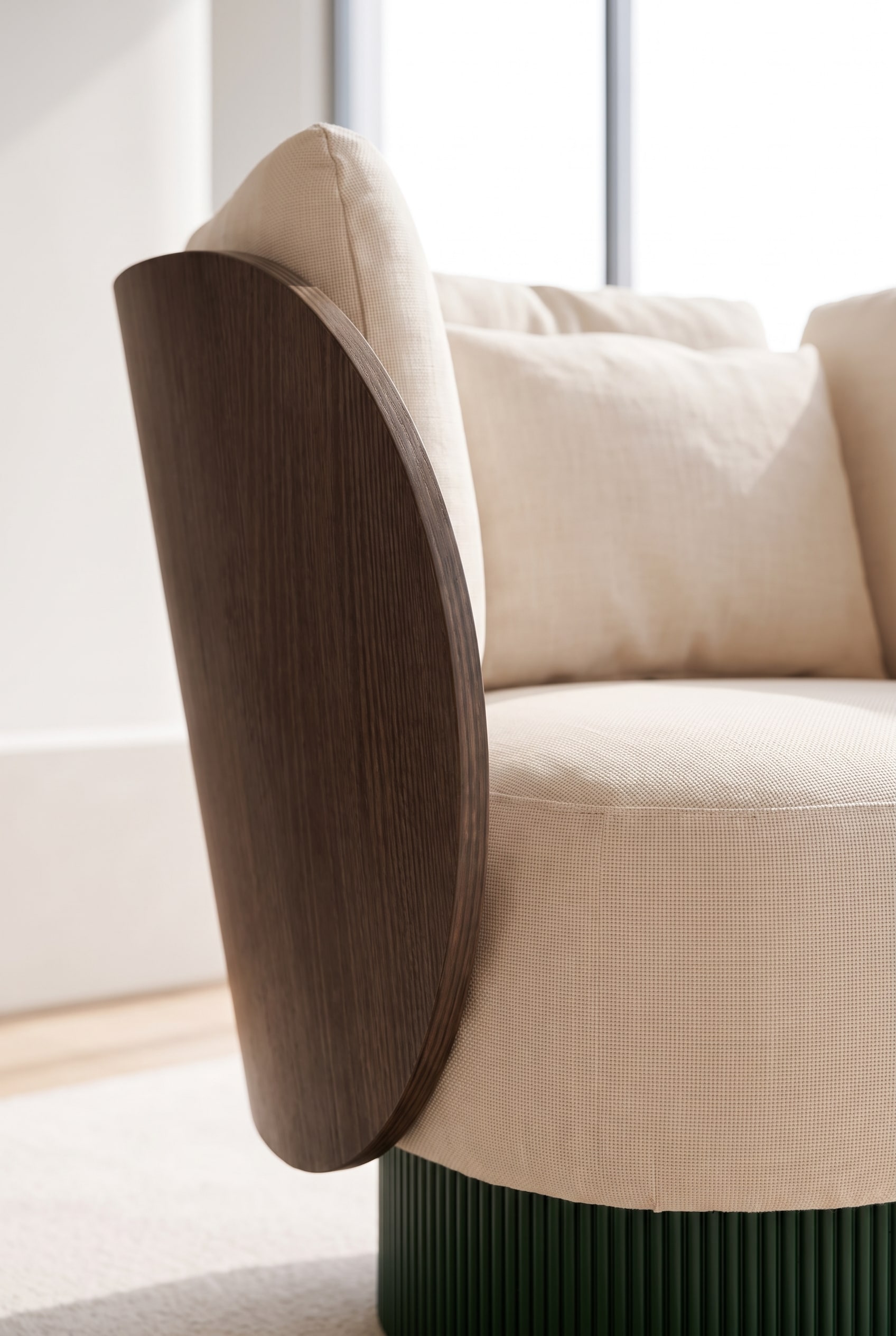 Gros plan de la combinaison de mat&eacute;riaux : bois courb&eacute;, socle rainur&eacute; et tissu premium beige.