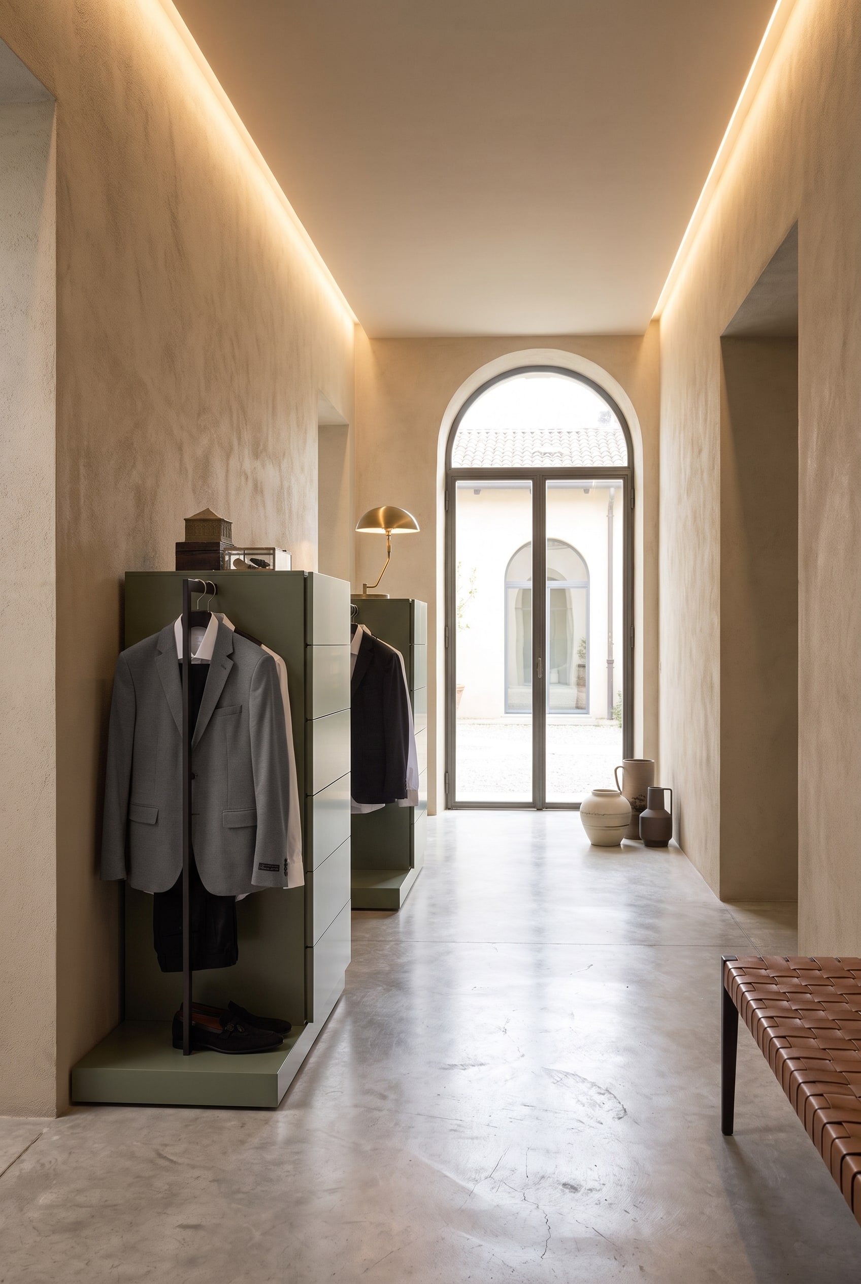 Couloir avec une commode haute verticale, intégrant latéralement une tringle à vêtements noire en métal avec des vestes suspendues