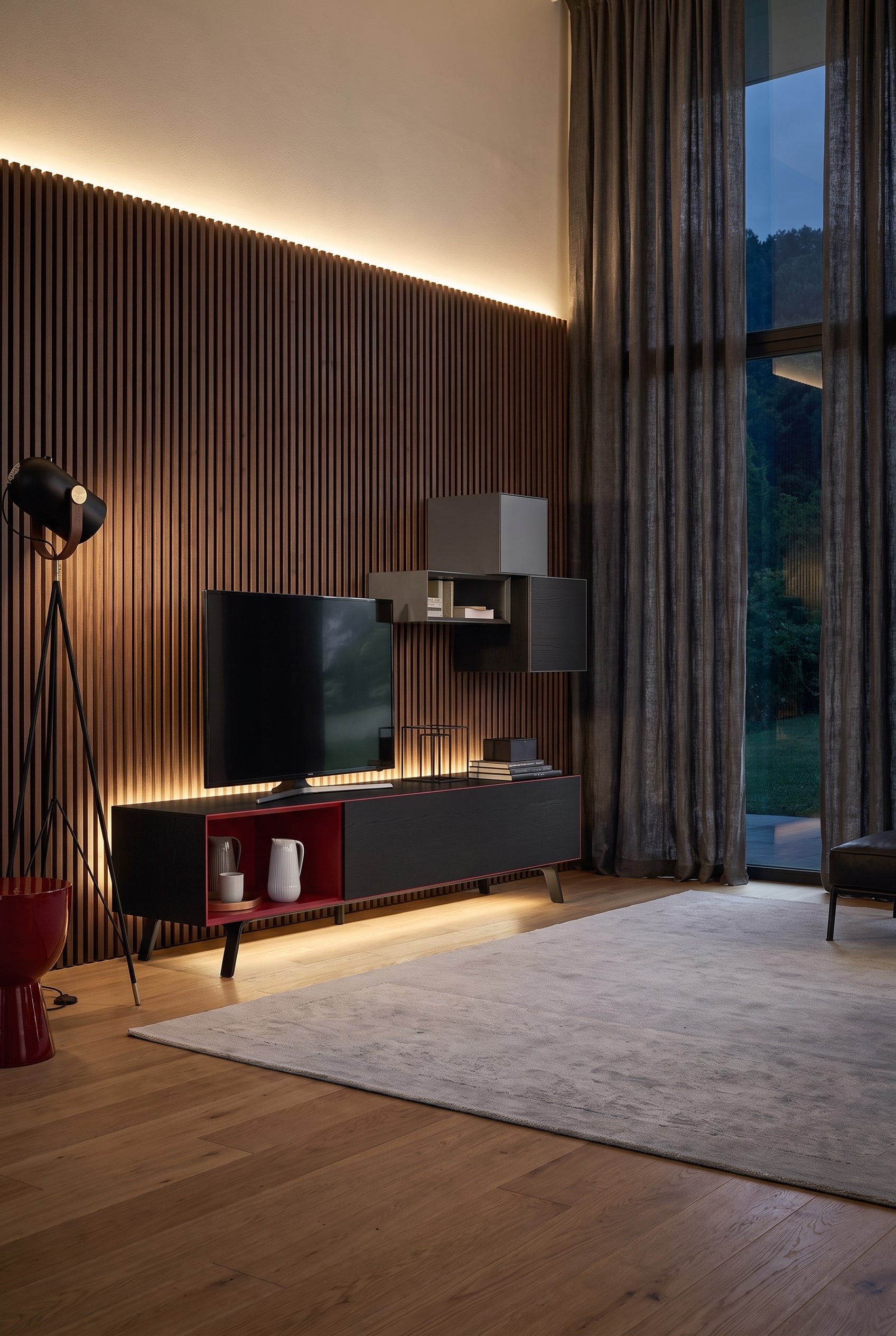 Grand salon le soir avec un meuble bas marron fonc&eacute;, un panneau TV pivotant, un mur &agrave; lattes &eacute;clair&eacute; en arri&egrave;re-plan et de lourds rideaux aux fen&ecirc;tres