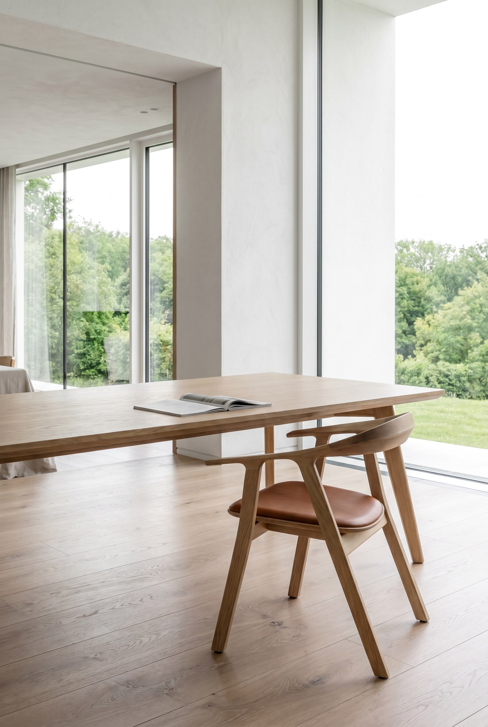 Salle à manger moderne avec table à manger en bois et chaises en bois Prostoria Rhomb en chêne avec revêtement en cuir marron sous une lumière du jour claire