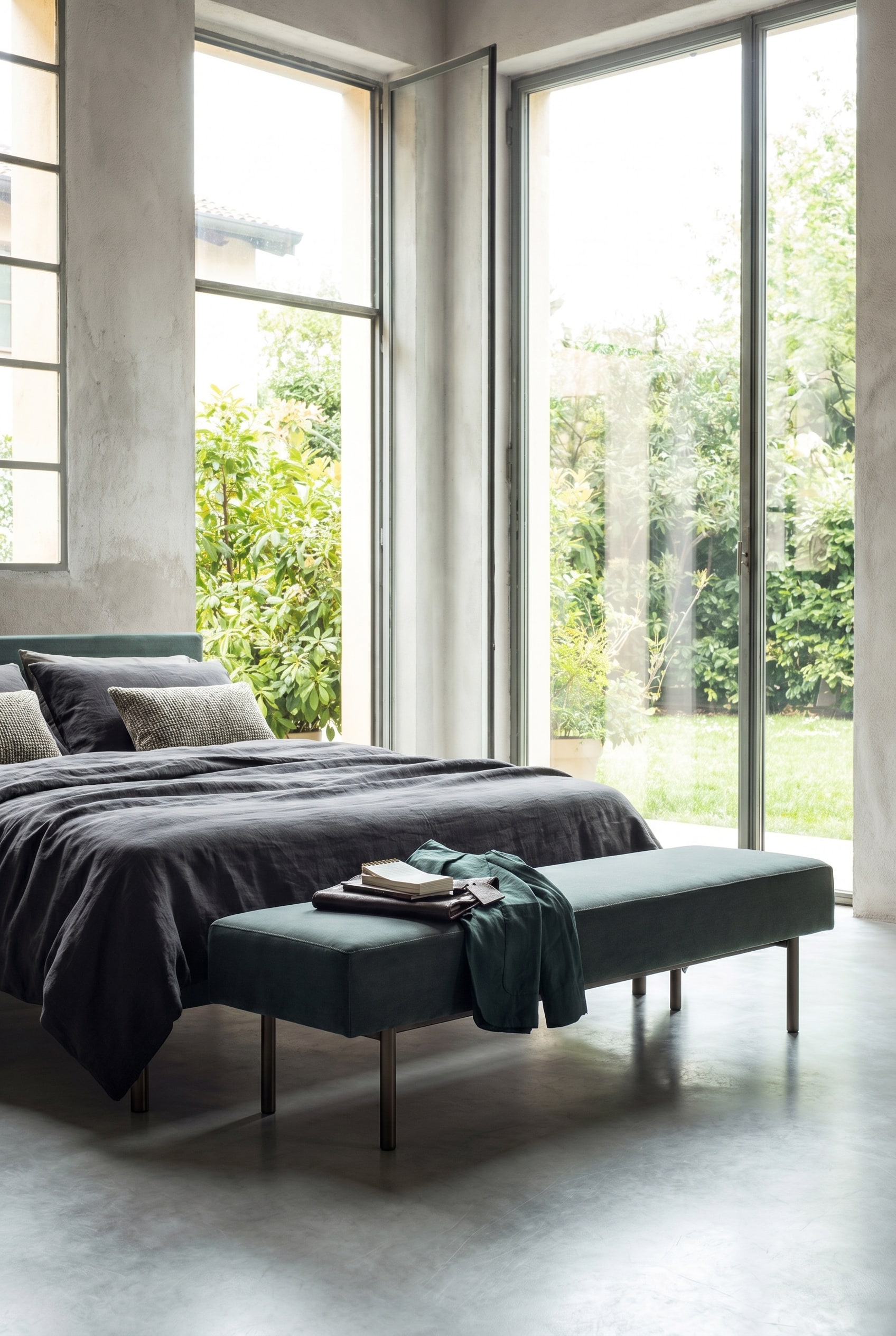 Banc rembourr&eacute; &eacute;l&eacute;gant et minimaliste avec des pieds fins au bout d'un lit dans une chambre moderne