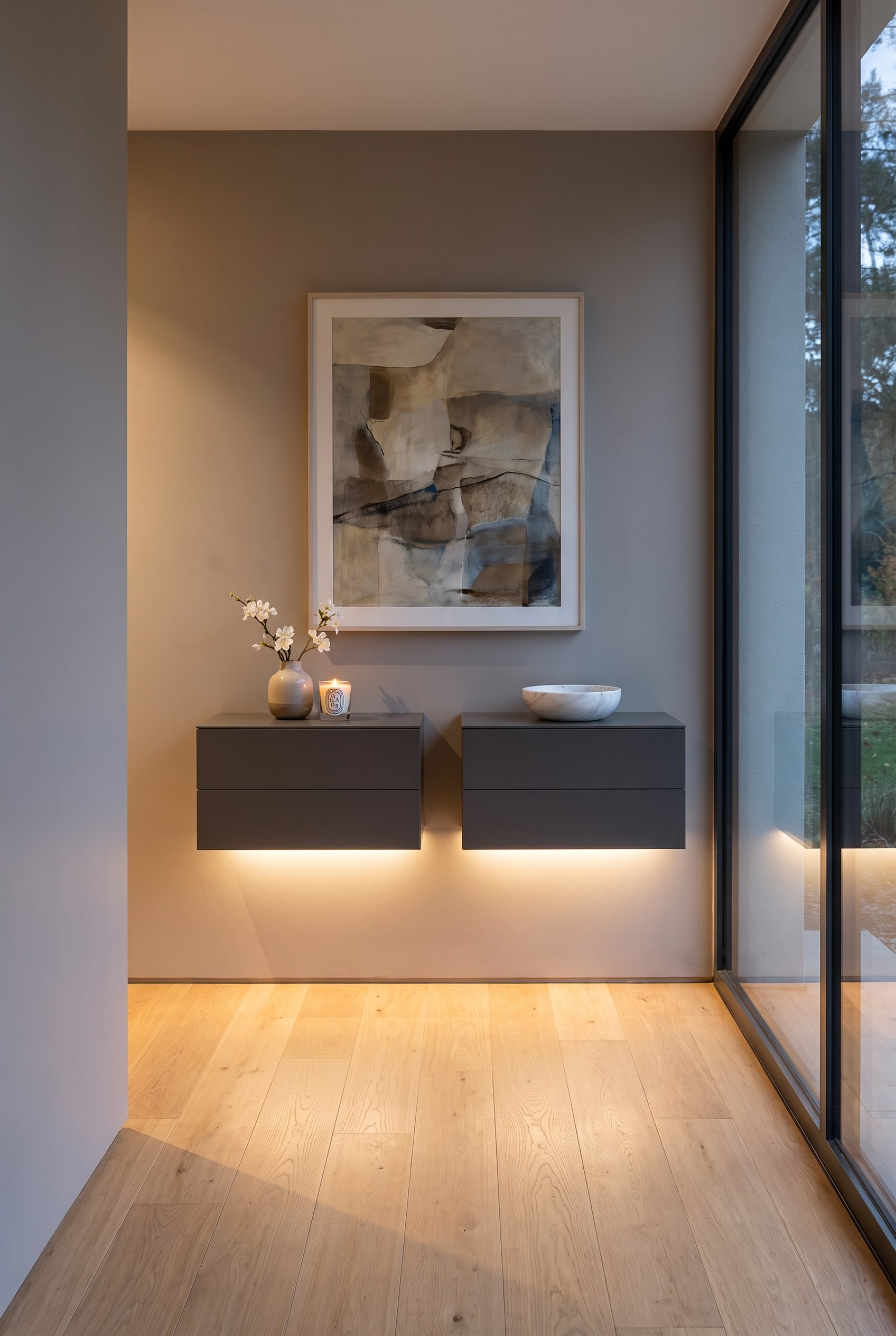 Une commode suspendue moderne et sans poign&eacute;e &agrave; deux tiroirs sur le mur d'un couloir &eacute;troit, sous la commode brille un &eacute;clairage indirect doux.