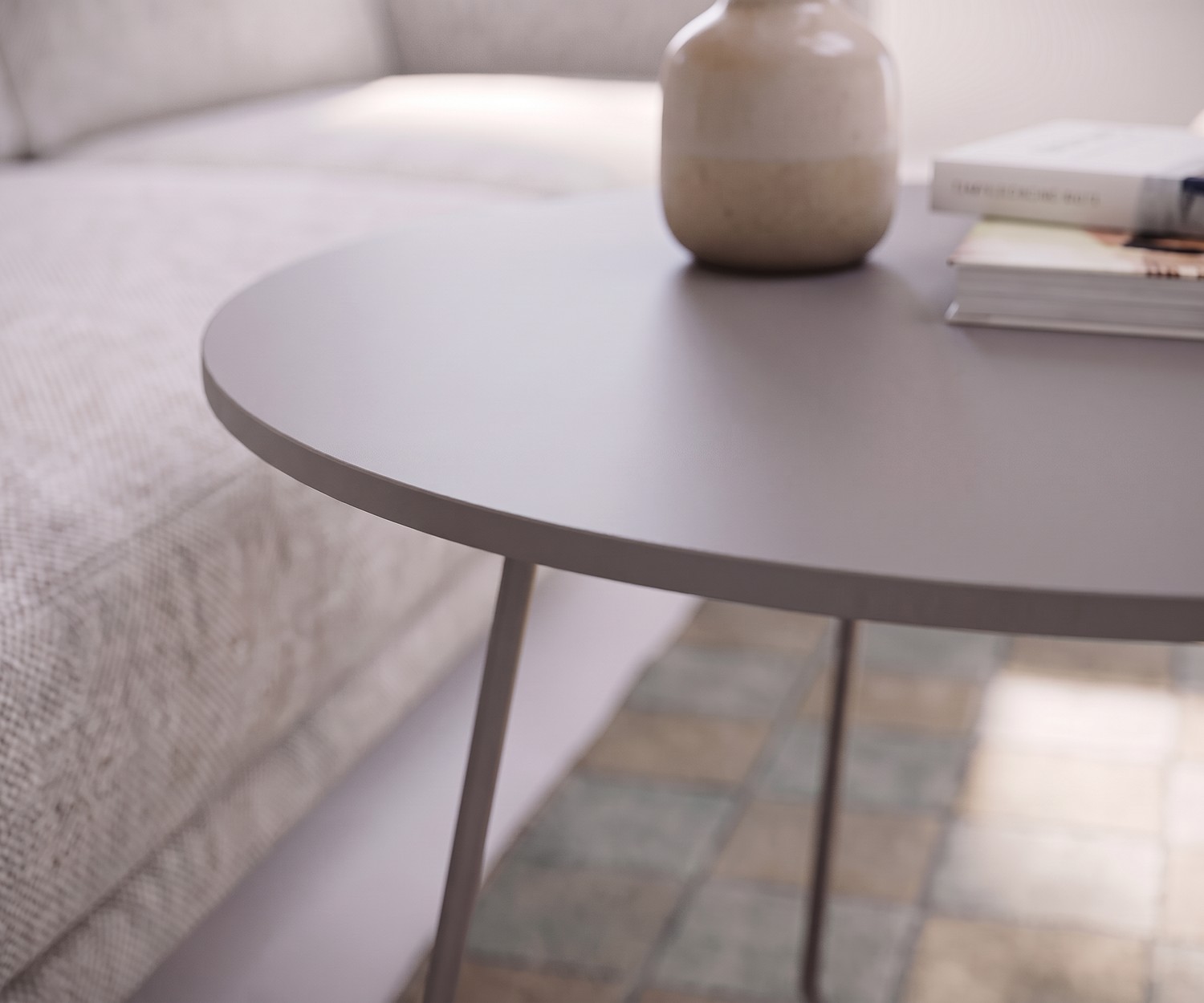 Table basse Orbis de Novamobili en gris Table basse Orbis Novamobili comme table d'appoint de salon près du canapé, plateau rond gris mat avec un vase.