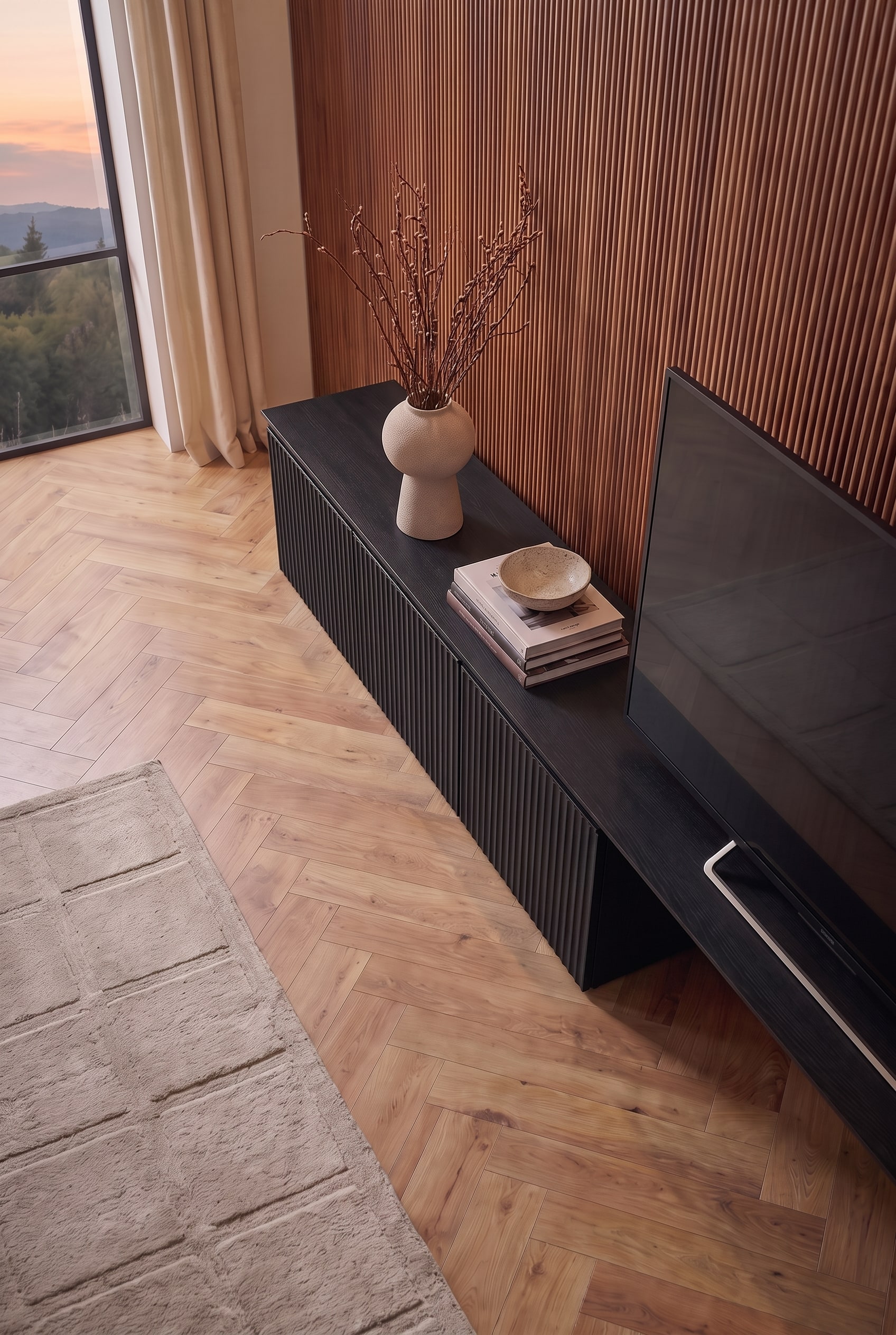 Vue oblique sur le lowboard TV noir. Des livres, une coupelle et un vase animent la surface à côté de l'écran.