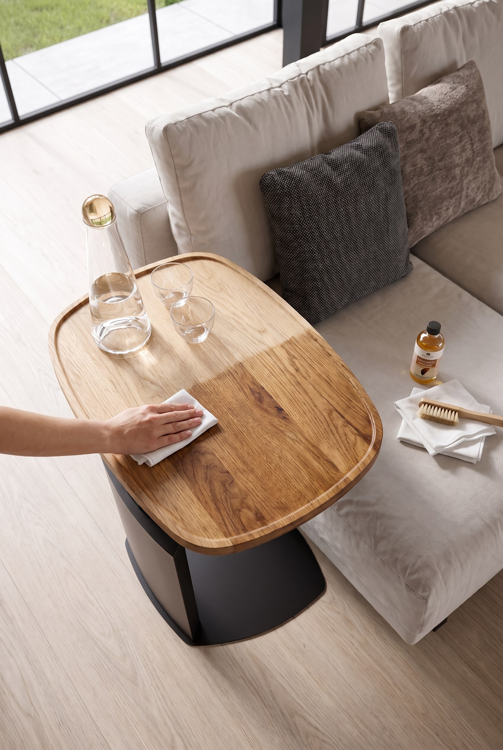 Gros plan : Une main applique délicatement de l'huile pour bois sur un plateau de table en bois massif non traité, avec un chiffon non pelucheux et des mouvements circulaires.