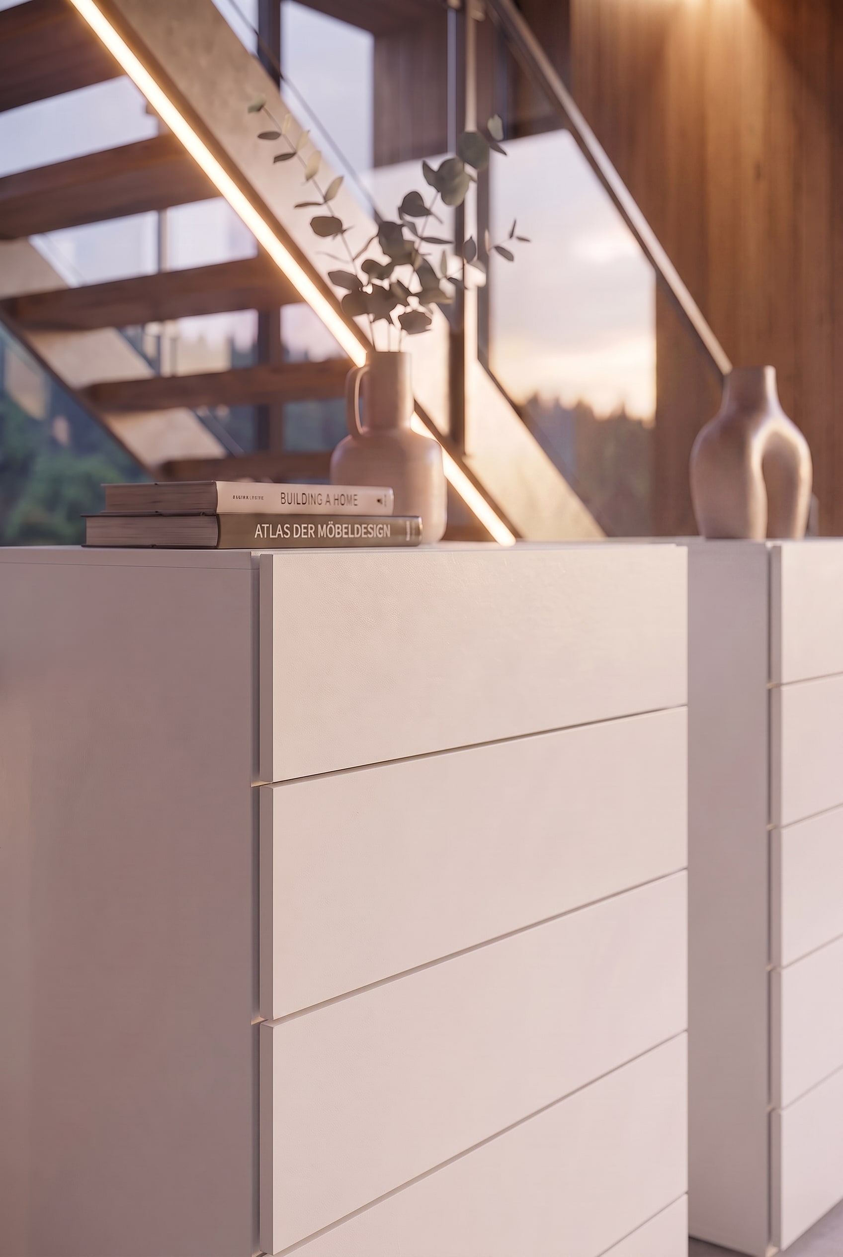 Détail d'une commode blanche avec des livres de design et un vase en céramique sous la lumière chaude du soleil.
