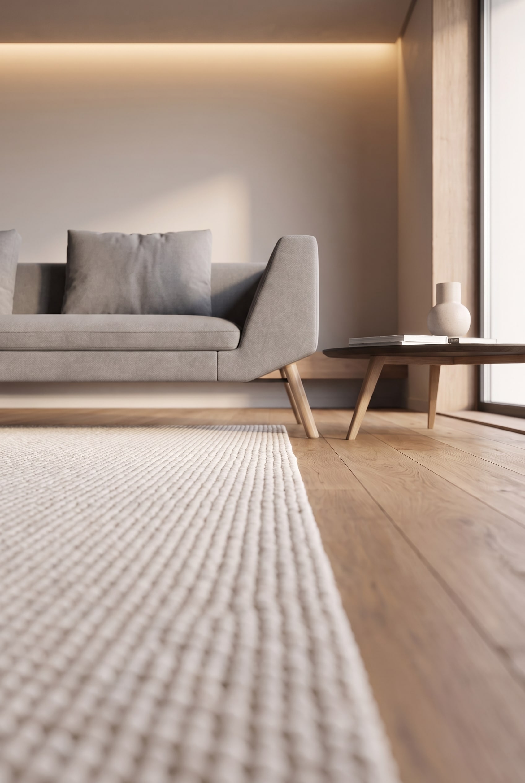 Gros plan d'un pied de canapé avant sur un tapis clair, tandis que le pied arrière repose sur un parquet en chêne.
