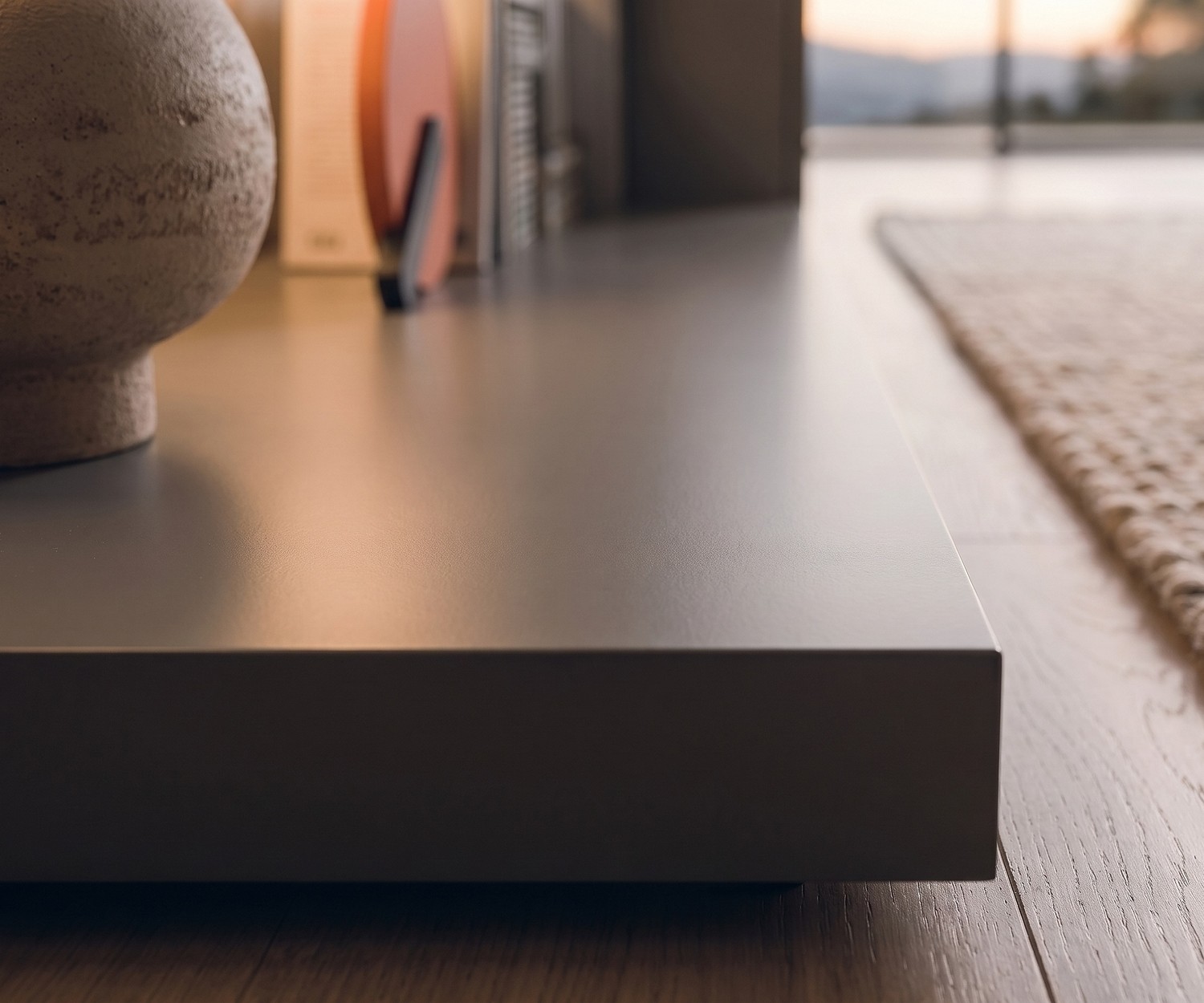 Podium TV Livitalia Easy pour le salon. Socle bas moderne gris foncé posé sur un sol en parquet.
