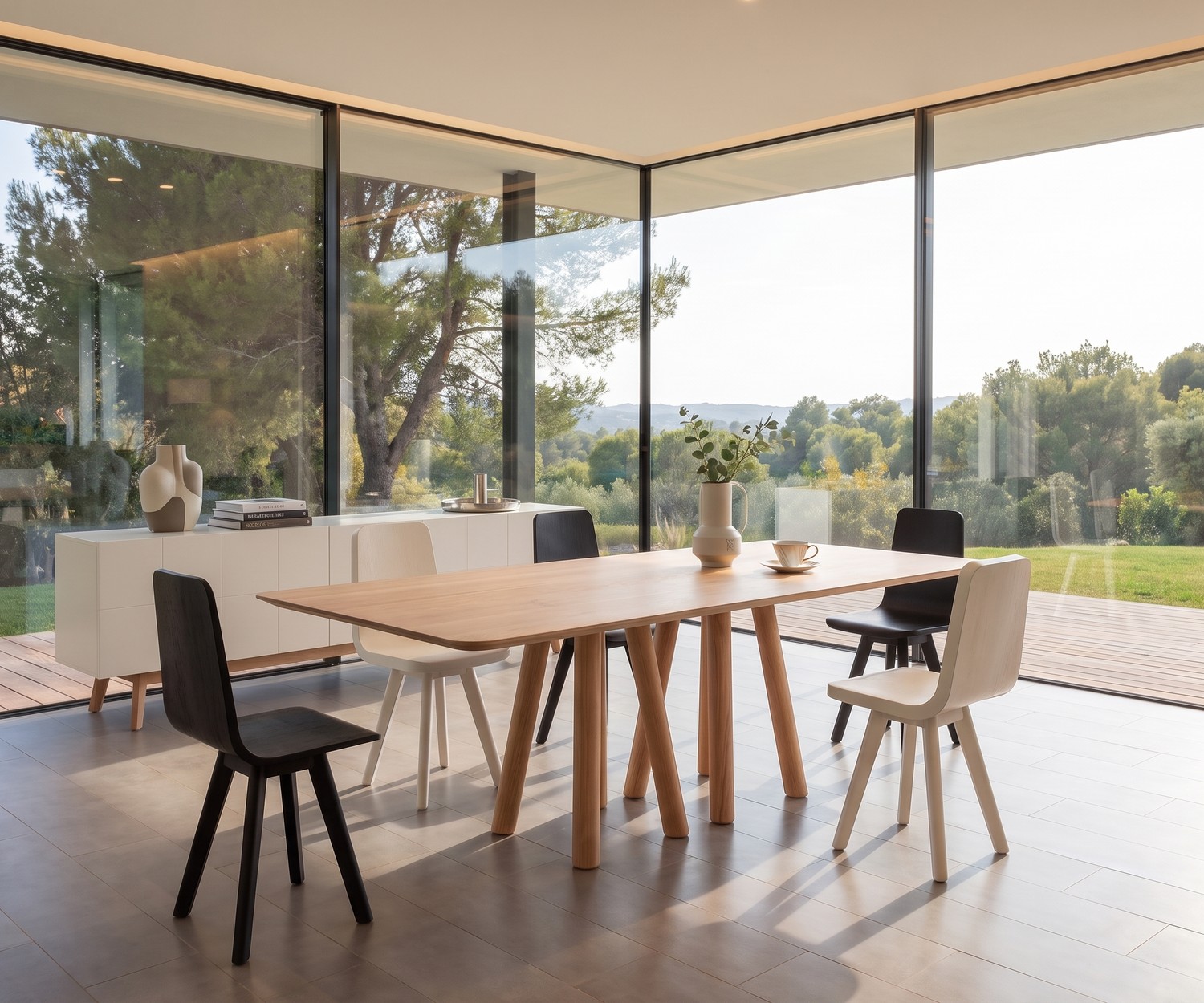 Table de repas design al2 mos-i-ko en bois dans une salle à manger moderne, avec grandes baies vitrées et chaises.