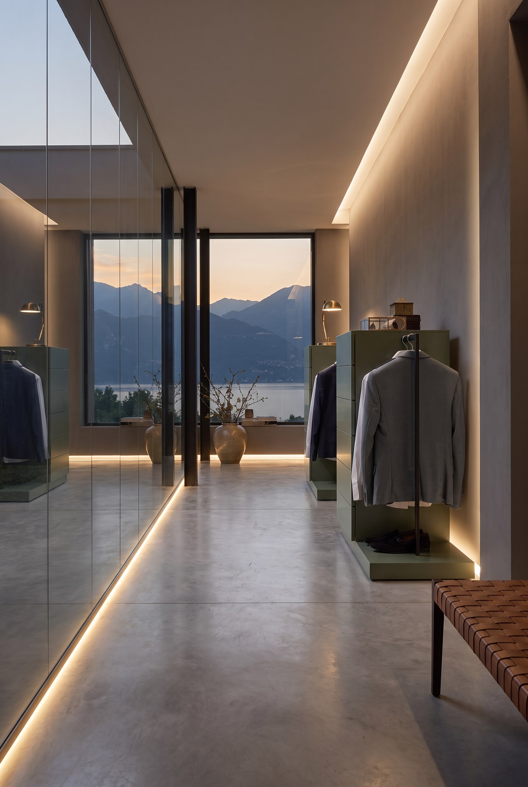 Deux commodes vert olive avec tringles &agrave; v&ecirc;tements dissimul&eacute;es dans un couloir moderne avec un mur miroir et une vue sur la montagne &agrave; travers la fen&ecirc;tre.