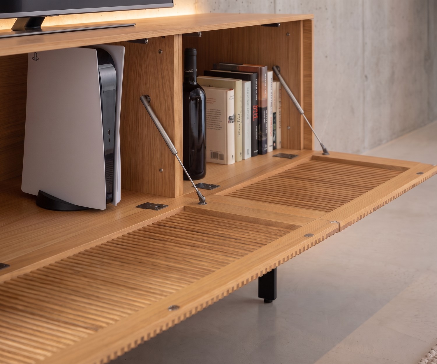 Meuble TV lowboard Punt Malmö en chêne avec porte abattante à claire-voie et rangement pour console dans un salon moderne.