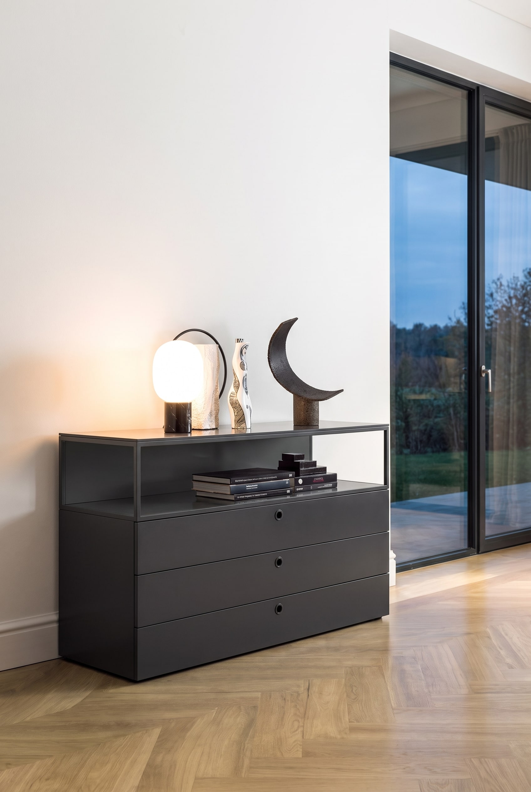 Salon moderne avec commode noire mate profonde devant un mur blanc sur un parquet clair