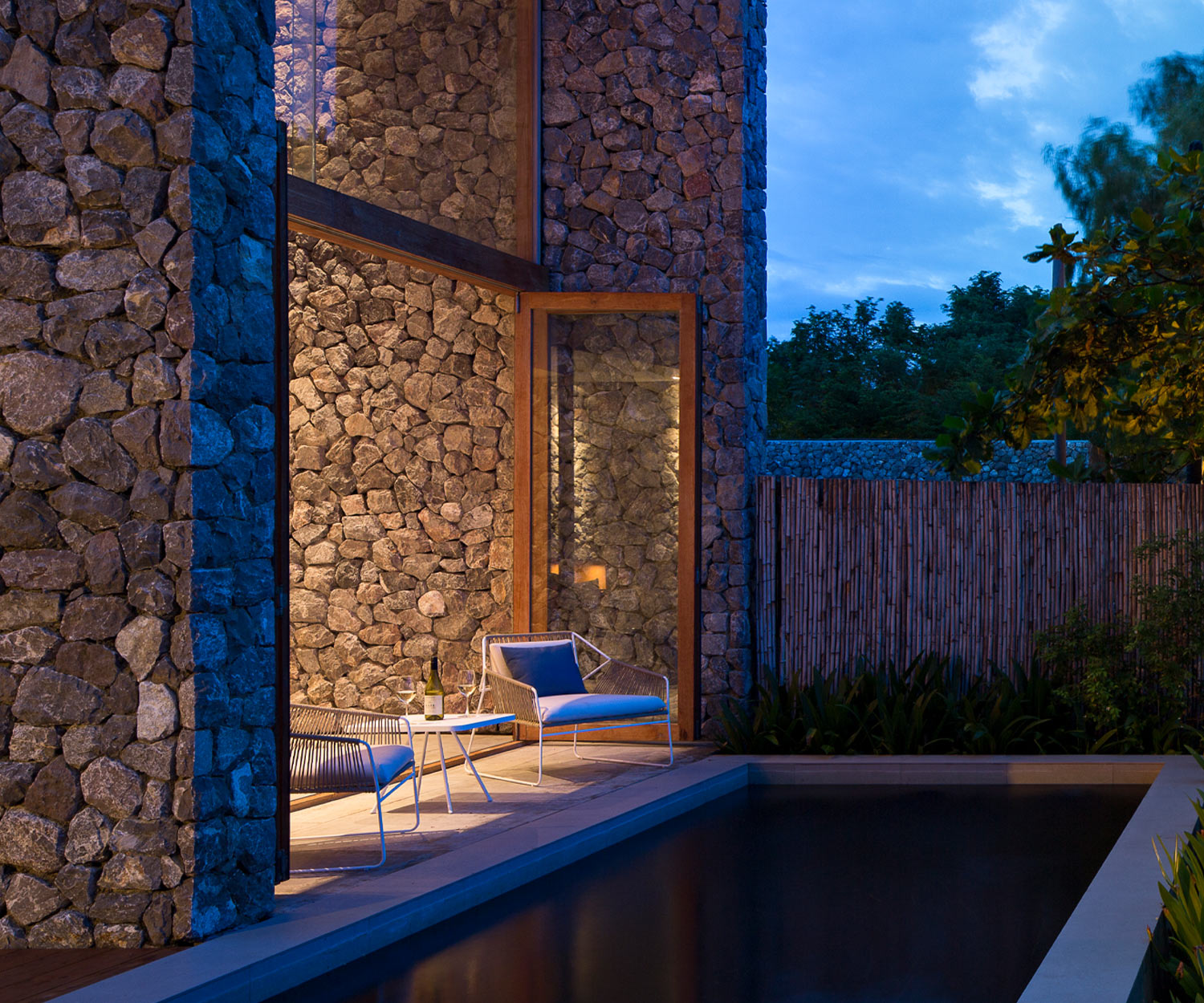 Witte Sandur buitenstoel van Oasiq bij het zwembad in de avond Witte Sandur buitenstoel van Oasiq bij het zwembad in de avond