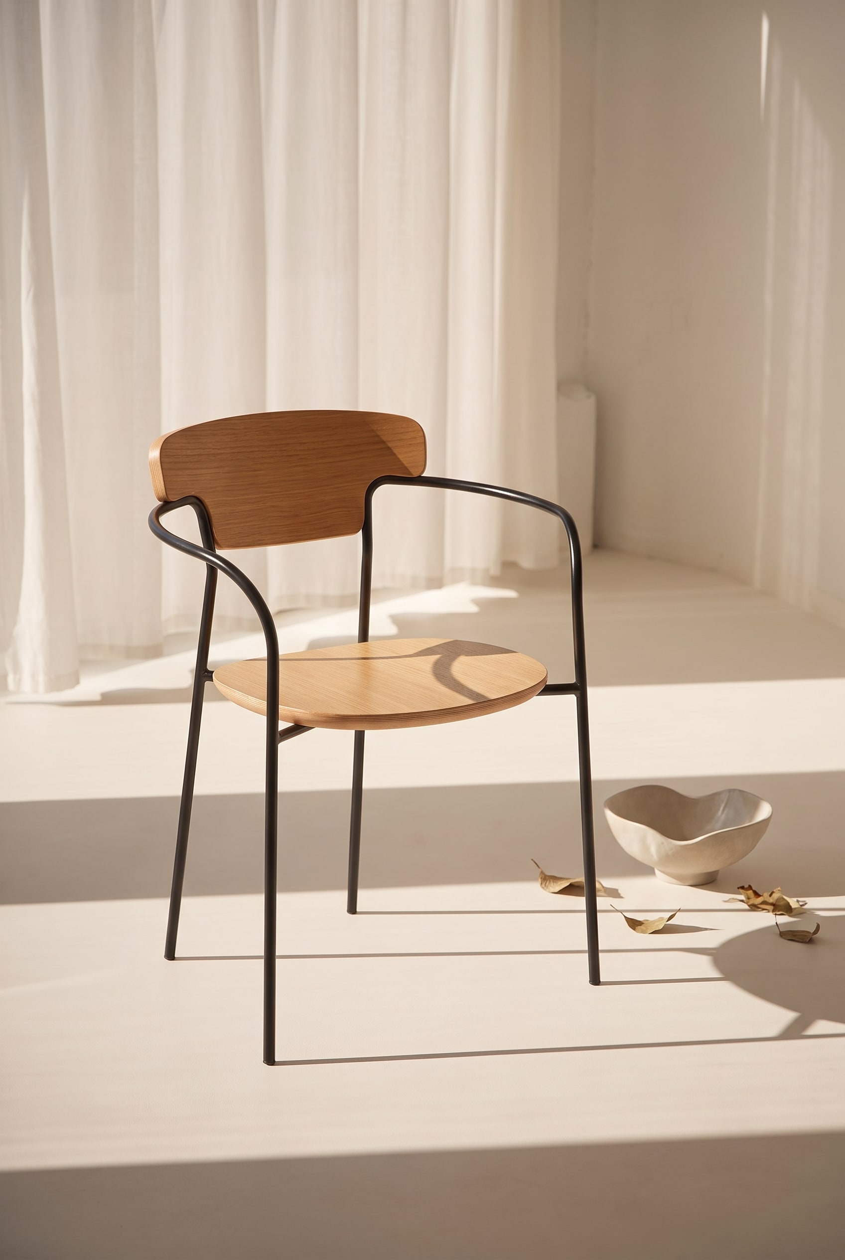 Pièce lumineuse avec une chaise de salle à manger en bois de chêne avec un dossier incurvé et une structure en métal noir