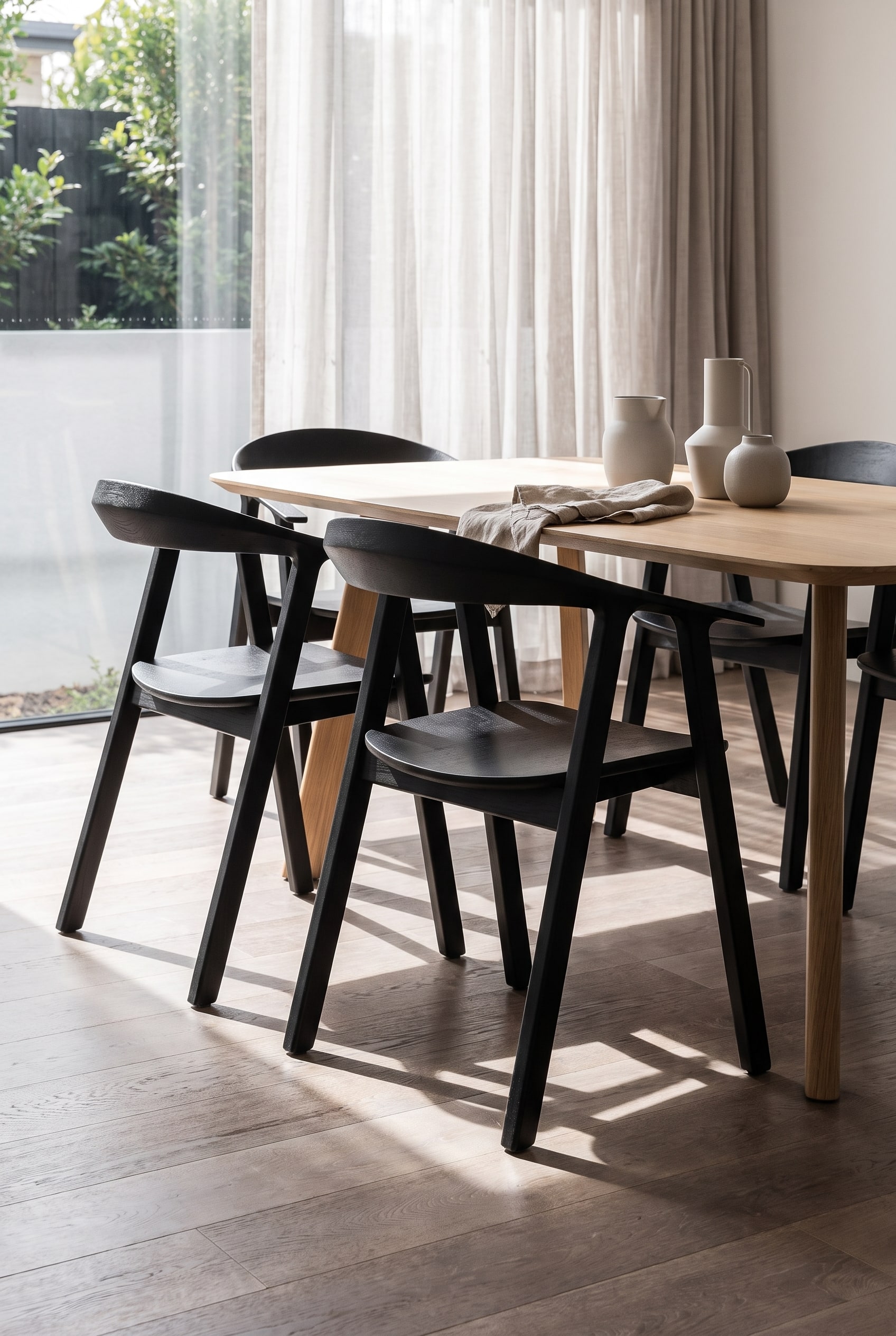 Un espace repas moderne et ouvert vu de l'arrière, où des chaises avec un dossier géométrique en losange créent un jeu d'ombres.