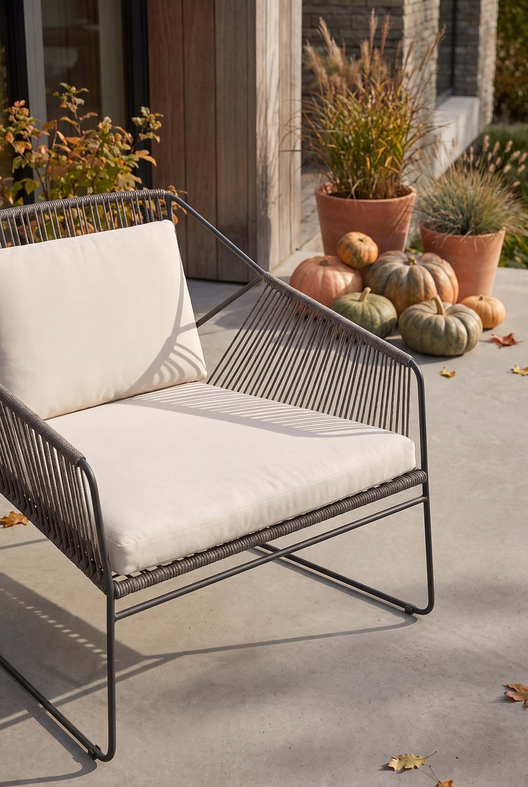 Chaise de jardin avec tressage de corde aéré et cadre en acier inoxydable sur un sol en béton à côté de plantes