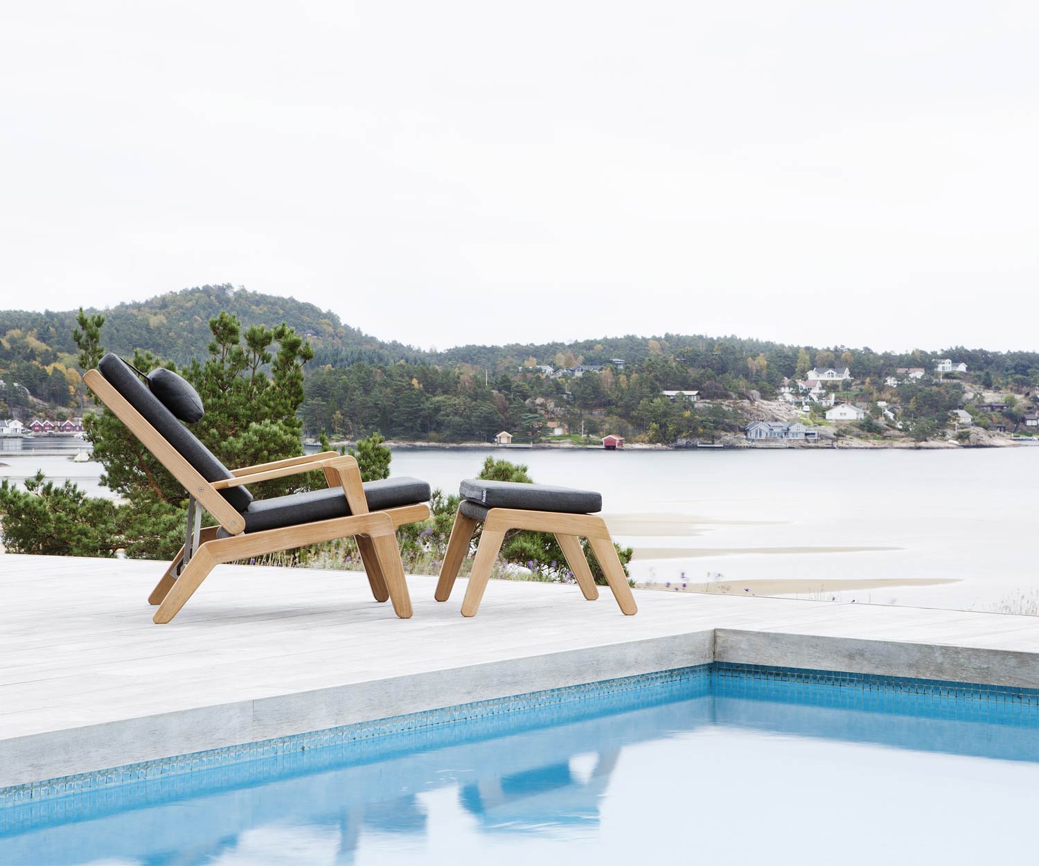 Oasiq Chaise longue Skagen Design en teck avec tabouret Skagen au bord de la piscine Oasiq Chaise longue Skagen Design en teck avec tabouret Skagen au bord de la piscine