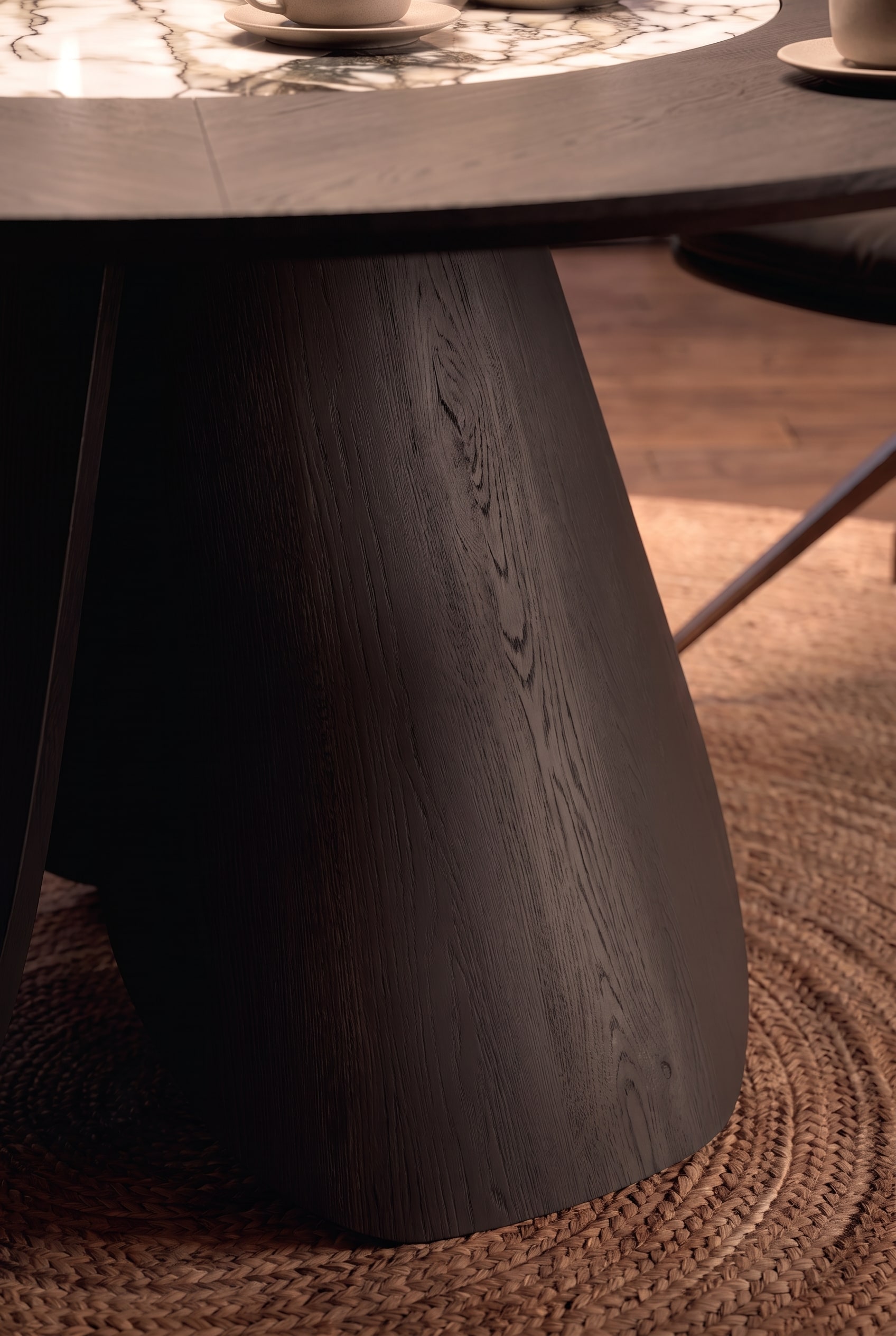 Gros plan du pied de table massif, incurv&eacute; vers l'int&eacute;rieur, en bois teint&eacute; fonc&eacute; avec veinure visible.